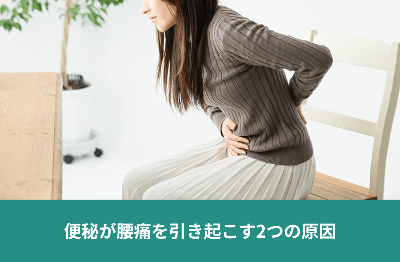 便秘が腰痛を引き起こす2つの原因。片手を腰に、もう一方の手を腹部に添える人。